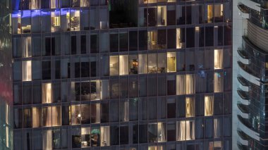 Ofis ve apartmanın gece görüşü. Pencereleri yanıp sönen gökdelenli ve içinde insanlar olan bir gökdelen. Yukarıdan hava görünümü