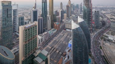 Sheikh Zayed Yolu yakınlarındaki binaların silueti ve Dubai, BAE 'deki hava gününden geceye geçiş. Günbatımından sonra finans merkezinde ve şehir merkezinde park yeri olan modern kuleler ve gökdelenler.