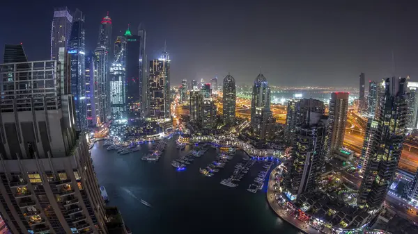 Dubai Marina gece geçiş timelapse havadan üst görünümü. Dubai, Bae yüzen yatlar ve tekneler ile gezinti ve kanal. Işıklı modern kuleler ve yolda trafik