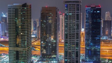 Jumeirah gölükuleleri konut ve ofis binaları Dubai'de gün doğumundan önce gündüz geçiş timelapse ilçe gece. Işıklı modern gökdelenler ile yukarıdan havadan panoramik görünüm