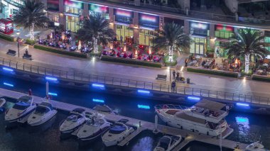 Dubai Marina Havaalanı 'ndaki restoranlarla rıhtım gezintisi. Kanalda yüzen tekne ve yatlar. Dubai, Birleşik Arap Emirlikleri