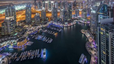 Dubai Marina gökdelenleri ve Jumeirah göl kulelerini aydınlattı ve Birleşik Arap Emirlikleri 'nin en üst düzey hava gece zaman çizelgesinden panoramik görüntüler elde etti. Yolda trafik ve yüzen yatlar.