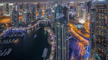 Dubai Marina gökdelenleri ve Jumeirah göl kulelerini aydınlattı ve Birleşik Arap Emirlikleri 'nin en üst düzey hava gece zaman çizelgesinden panoramik görüntüler elde etti. Yolda trafik ve yüzen yatlar.