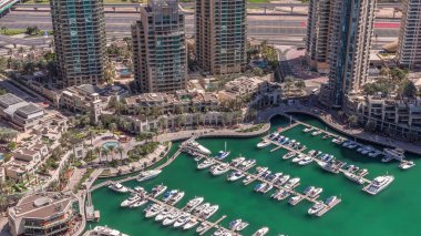 Dubai Marina Limanı 'nda liman kenarında modern yatlar var. Kanalda yüzen tekneler kuleleri ve gökdelenleri çevreledi..