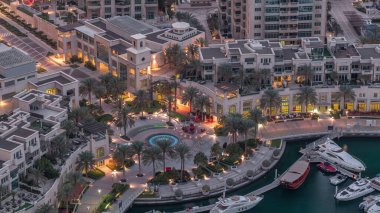 Dubai Marina Yürüyüşü 'nde çeşme ve palmiyeli Top View gece gündüz geçiş zamanı. Sabahları yat ve teknelerle aydınlatılmış.
