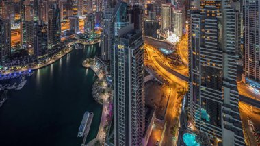 Dubai Marina, Birleşik Arap Emirlikleri 'nde gökdelenleri ve Jumeirah göl kulelerini aydınlatmıştır. Yolda trafik ve yüzen yatlar.