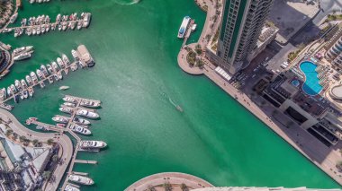 Dubai Marina Limanı 'nda liman kenarında modern yatlar var. Kanalda yüzen tekneler kuleleri ve gökdelenleri çevreledi..
