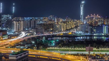 Palm Jumeirah Karayolu köprü hava gece timelapse. Trafik ve şantiye ile Internet şehirden görünüm. Dubai, Birleşik Arap Emirlikleri