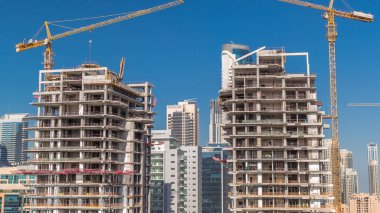 İnşaat halindeki gökdelenlerin havadan görünüşü Dubai 'de dev vinçler zaman ayarlı. Arka planında mavi gökyüzü olan bir işletme bölgesi. Birleşik Arap Emirlikleri