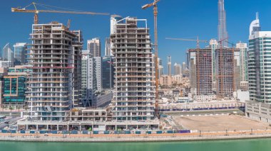 İnşaat halindeki gökdelenlerin havadan görünüşü Dubai 'de dev vinçler zaman ayarlı. Arka planda şehir merkezi olan bir işletme alanı. Birleşik Arap Emirlikleri