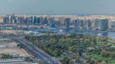 Deira 'daki yeni modern binaların ve arka planda deniz bulunan yeşil parkın hava manzarası güneşli Dubai Creek, Dubai' de, Birleşik Arap Emirlikleri 'nde