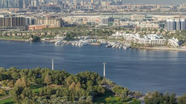 Güneşli bir günde yeşil parkın yanındaki mavi nehrin hava manzarası. Dubai, Dubai 'de mavi gökyüzü Timelapse, Birleşik Arap Emirlikleri.