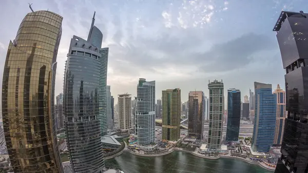 Residential and office buildings in Jumeirah lake towers district day to night transition timelapse in Dubai. Aerial panoramic view from above with modern skyscrapers