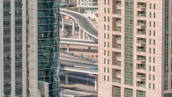 Residential and office buildings in Jumeirah lake towers district morning timelapse with in Dubai. Aerial panoramic view from above with traffic on a road between modern skyscrapers