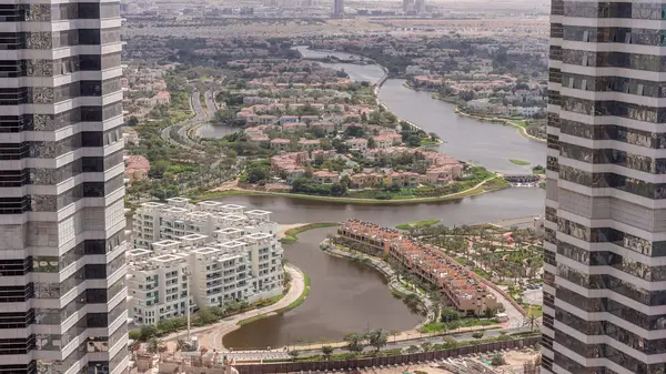 Aerial view of apartment houses and villas between tall towers in Dubai city timelapse near jumeirah lake towers district, United Arab Emirates. Top fiew from skyscraper