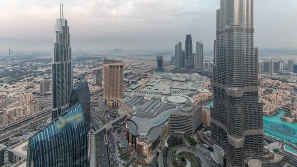 Şehir merkezindeki Dubai 'nin panoramik ufuk çizgisi manzarası alışveriş merkezi, çeşmeler ve Burj Khalifa hava gününden geceye geçiş zamanı. Günbatımından sonra modern gökdelenler ve bulutlu gökyüzü