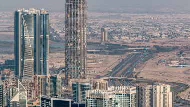 Dubai'deki iş bölümü kulelerinin panoramik havadan görünümü akşam saatinde. Bazı gökdelenlerin çatı görünümü, otoyoldaki trafik ve yapım aşamasındaki yeni kuleler.