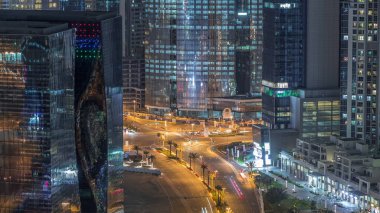 Dubai 'deki bir kavşakta gece vakti hava üstü şehir trafiği. Yukarıdan yol ayrımı, otomobil trafiği ve gökdelenler