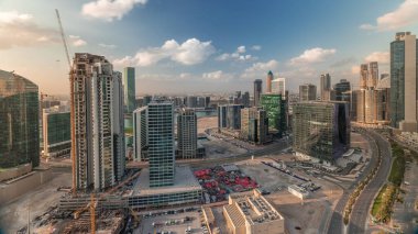 Dubai 'nin iş hanı kuleleri sabahları havadan kontrol ediliyor. Bazı gökdelenlerin çatı manzarası ve inşaat halindeki yeni kuleler. Mavi gökyüzünde bulutlar ve yollarda trafik