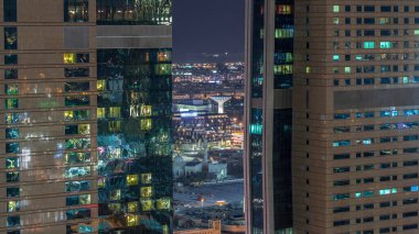Dubai şehir merkezindeki gökdelenler gece saatlerinde harika bir hava manzarası ve Dubai, Birleşik Arap Emirlikleri 'nin pencerelerinde ışık var. Aydınlatılmış modern kuleler ve cami. Arka planda şehir yürüyüşü