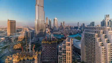 Gün batımında Dubai şehir merkezindeki Skyline manzarası. Alışveriş merkezi, çeşmeler ve Burj Khalifa 'nın hava saatleri. Modern gökdelenler ve inşaat alanı. Akşamları mavi gökyüzü