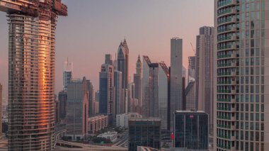Gündoğumunda modern gökdelenleri aydınlatan Dubai Finans Merkezi bölgesi. Şehir merkezinden gökyüzü manzarası ve kulelerden yansıyan güneş.