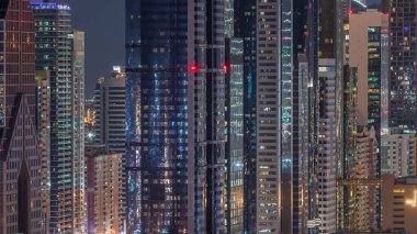Dubai Finansal Merkezi semti, aydınlatmalı modern gökdelenler, gece zaman çizelgesi. Şehir merkezinden gökyüzü manzarası ve kulelerin ışıkları