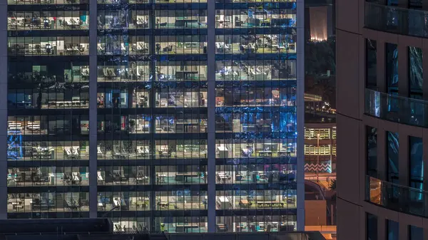 深夜のオフィスビルの外観にはインテリアライトが設置され 超高層ビルの夜のタイムラプスの中で働く人々 多くの照明付き窓から上からの航空機のクローズアップ — ストック写真
