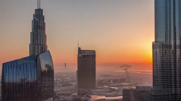 Dubai downtown street during sunrise with busy traffic and skyscrapers around timelapse. Modern road and urban buildings with mall aerial view with morning haze. Sheikh Mohammed bin Rashid Blvd
