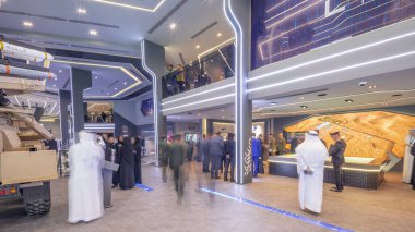 Abu Dhabi, UAE - Feb 25, 2023: International Defence Exhibition and Conference, IDEX timelapse hyperlapse. Most strategically important tri-service exhibition. People inside Tawazun Council pavilion clipart