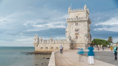 Belem Kulesi, Portekiz 'in Lizbon şehrinde Santa Maria de Belem bölgesinde bulunan bir takviyeli kuledir. Bulutlu bir günde insanlar rıhtımda yürüyor