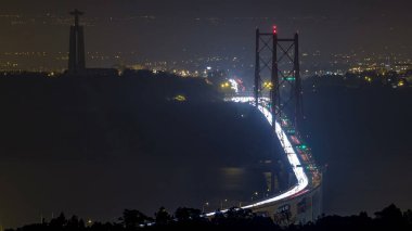 Panoramic view over Lisbon and Almada with traffic on illuminated April 25 bridge from a viewpoint in Monsanto night timelapse. Aerial top overview with Cristo Rei monument clipart