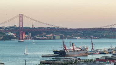 Lizbon ticari limanından geceye geçiş süresi, 25 Nisan Köprüsü, yük vinçli konteynırlar, Lizbon, Portekiz şehir treni. Gün batımından sonra hava görüntüsü