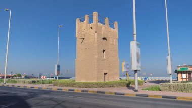 Ajman zaman kulesinin mavi gökyüzü ve yoldaki trafik hızını izleyin. Birleşik Arap Emirlikleri