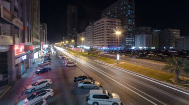 Otoparkı trafikte olan Ajman 'ın şehri. Köprüden hava manzarası, gece vakti aydınlatılmış binalarda ışıklar. Birleşik Arap Emirlikleri.