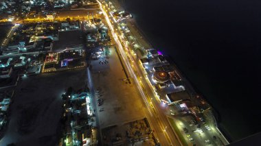 Panorama, Ajman 'ın çatıdan yola çıkan trafiği gece vakti aydınlık binalarda ışıkları olan şehir manzarasını gösteriyor. Birleşik Arap Emirlikleri.