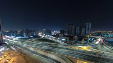 Ajman 'da büyük bir yol kavşağında trafik var. Gece vakti çatıdan hava manzaralı. Birleşik Arap Emirlikleri 'nde üst geçitle kesişen birçok araba var..