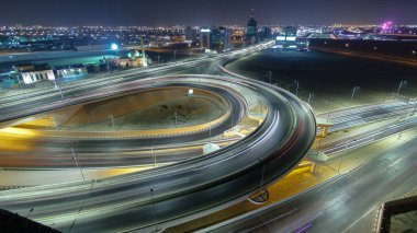 Panorama, Ajman hava sahasında büyük bir kavşakta trafiği gösteriyor. Gece vakti çatıdan görünüyor. Birleşik Arap Emirlikleri 'nde üst geçitle kesişen birçok araba var..