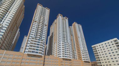 Ajman zaman ayarlı hiperhızlandırılmış modern yeni kuleler. Ajman 'ın yerleşim yeri ve ofis gökdelenleri olan şehir manzarası. Mavi gökyüzü. Birleşik Arap Emirlikleri.