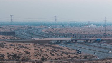 Gün batımından sonra Ajman 'dan Dubai' ye büyük bir şehirde, çöldeki karayolu trafiği günden geceye değişiyor. Ulaşım konsepti. Yukarıdan görüntüle
