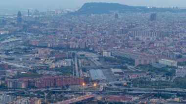 Day to Night Transition Timelapse of Barcelona and Badalona Skylines. Aerial View from Iberic Puig Castellar Village Viewpoint, Capturing Road Intersection, and Gradual Transition from Sunset to Night clipart