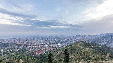 Evening Timelapse of Barcelona and Badalona Skylines. Aerial View from Iberic Puig Castellar Village Viewpoint, Revealing Roofs of Houses, and the Sea on the Horizon, Creating a Picturesque Panorama clipart