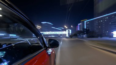 Hızlı sürüş yapan bir şehrin gece caddesinde, yüksek hızda ışık yansıtan bir yolda, hızlı sürüş yapan bir arabadan saçma sapan bir şehir görüntüsü. Modern bir şehrin hızlı ritmi. Bulanık hareket