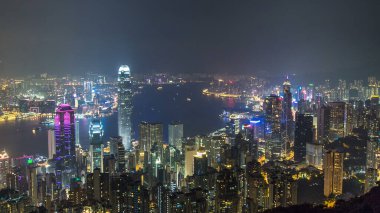 Gece vakti Victoria Limanı ve gökdelenlerin ışıklarıyla aydınlandığı Hong Kong şehrinin gökyüzü gökyüzü gökyüzü gökdelenleri dağın tepesinden görülebiliyor..
