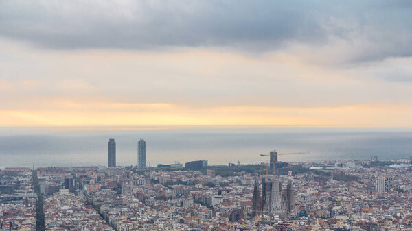 Panorama of Barcelona during sunrise timelapse, Spain, viewed from the Bunkers of Carmel on a cloudy morning with rays of light. Aerial top view from hill with sagrada familia cathedral. Colorful sky