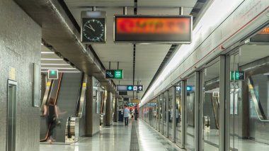 Central 'daki metro tren istasyonunda saat ve yürüyen merdiven, Hong Kong. MTR, Hong Kong 'daki en popüler nakliye aracı..