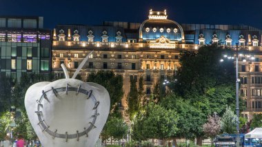 Anıtsal Reintegrated Apple Milan'ın Merkez Tren İstasyonu, Piazza Duca d'Aosta gece timelapse önünde heykel. Aydınlatılmış binalar. Yaz günü, yeşil ağaçlar