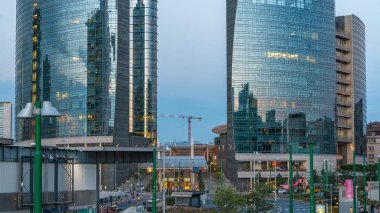 Milan Porta Nuova iş bölgesi gün gece geçiş timelapse Milan, İtalya, güneş battıktan sonra içinde modern gökdelenler ile manzarası. Yolda trafik. Işık içinde pencere eşiği. Köprüsü'nden Üstten Görünüm