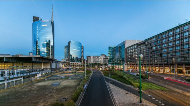 Milan panoramic skyline with modern skyscrapers in Porta Nuova business district day to night transition in Milan, Italy, after sunset. Traffic on the road. Light in windows. Top view from bridge clipart