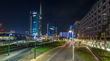 Milan skyline with modern skyscrapers in Porta Nuova business district night timelapse in Milan, Italy. Traffic on the road. Light in windows. Top view from bridge clipart